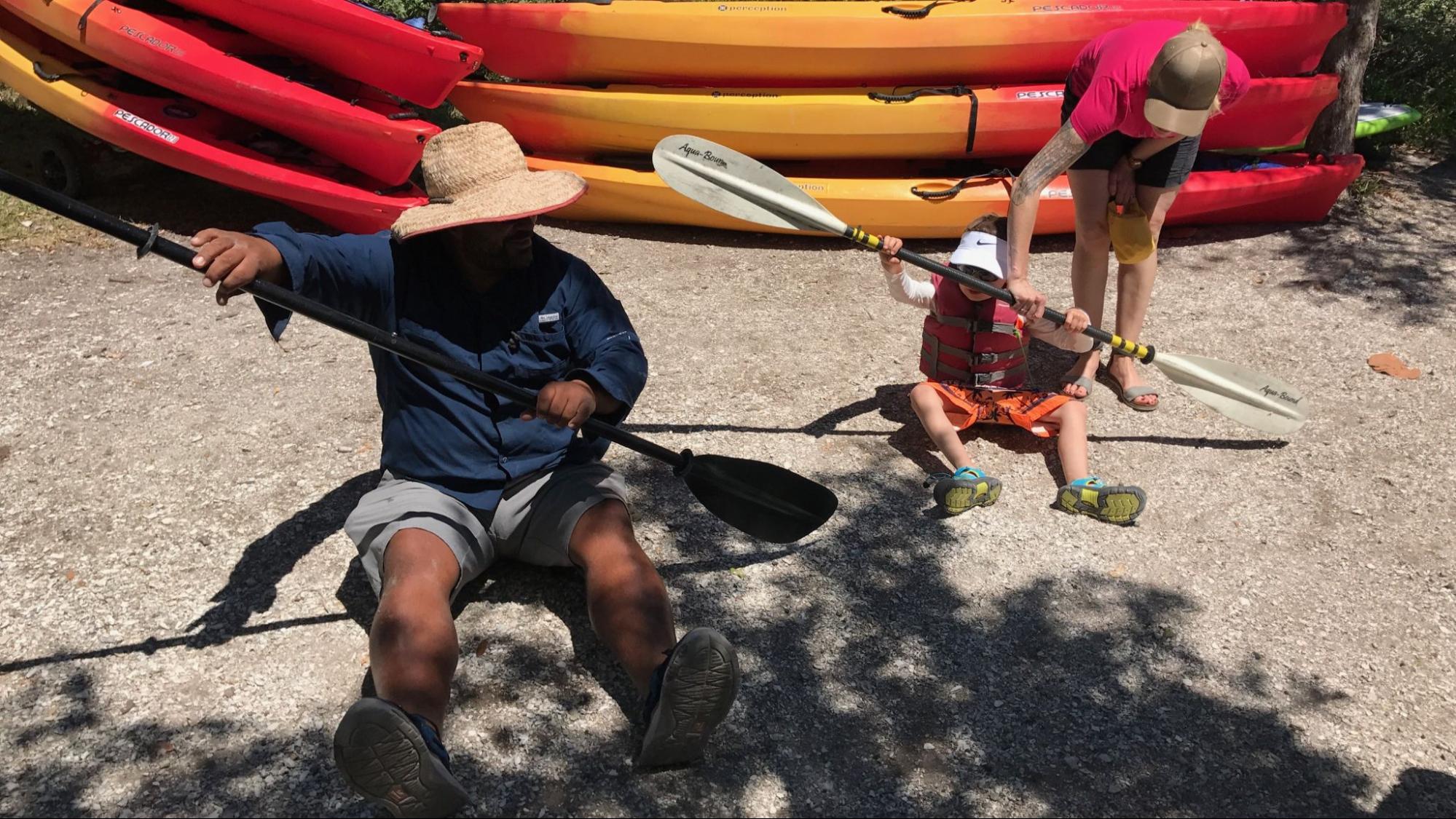 Expert guide teaching a child how to paddle a kayak